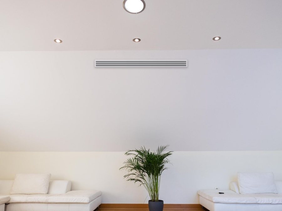 Pièce sous combles : une grille linéaire discrète dans le plafond, seule trace visible de l'installation